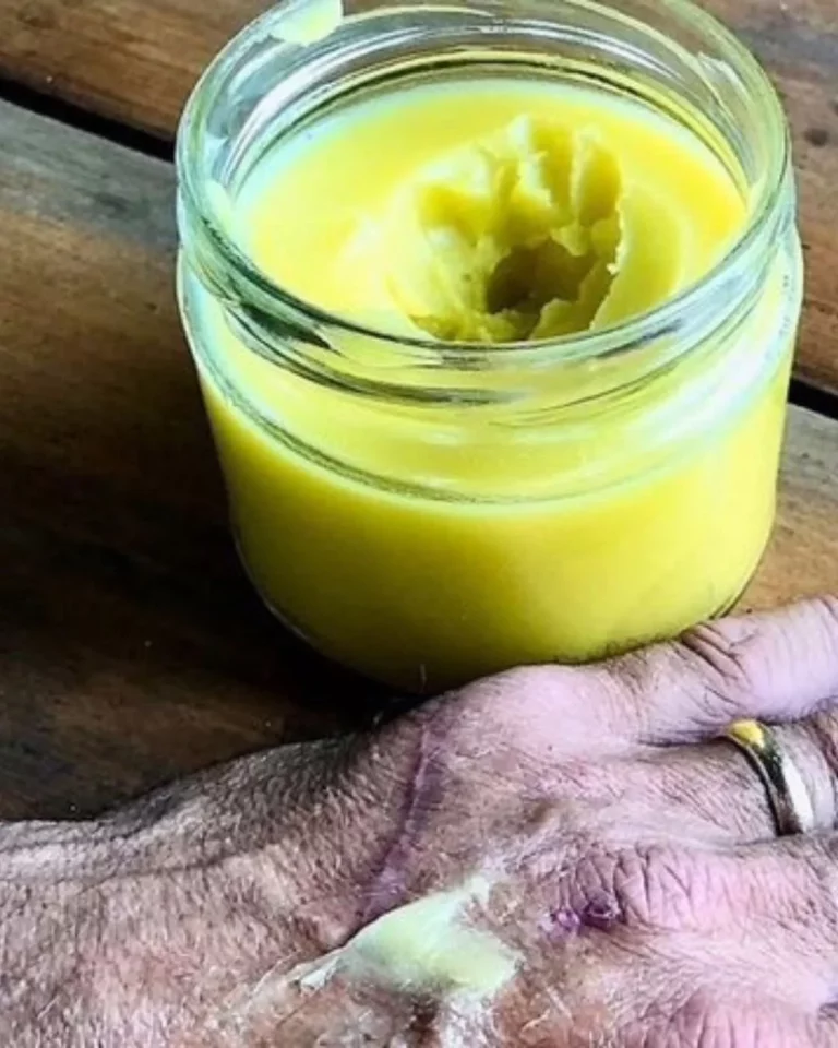 A natural herbal antibacterial ointment in a small jar with fresh herbs and plants.