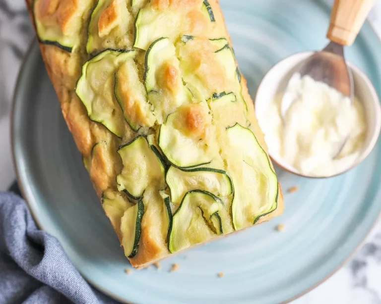 Moist and savory zucchini parmesan bread sliced on a wooden board.