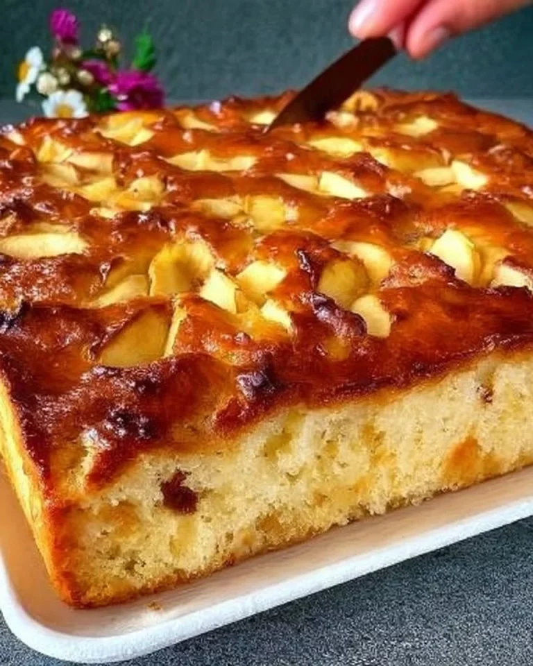 Freshly baked apple pie with golden crust and sliced apples on a wooden table.