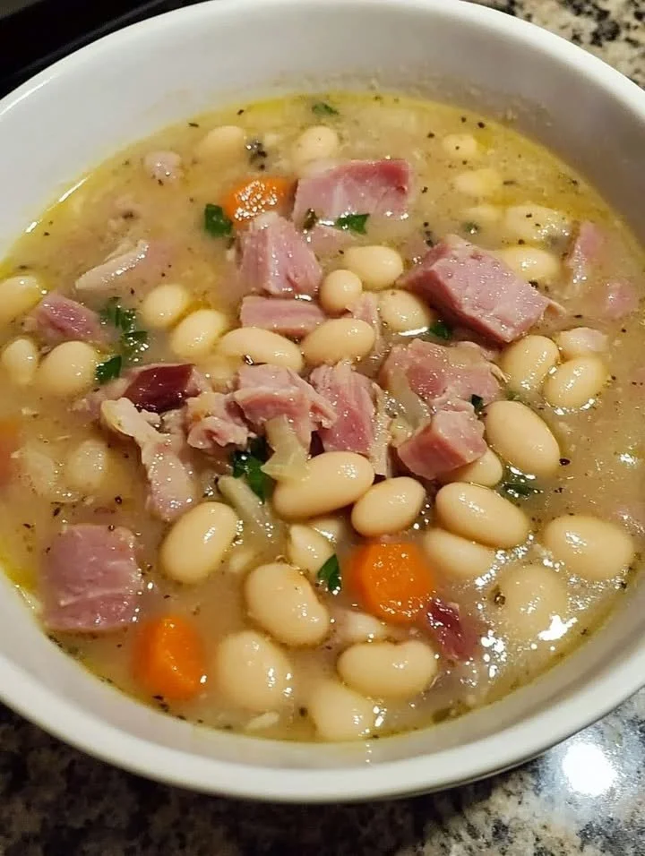 Bowl of Ham and White Bean Soup garnished with herbs and served hot.