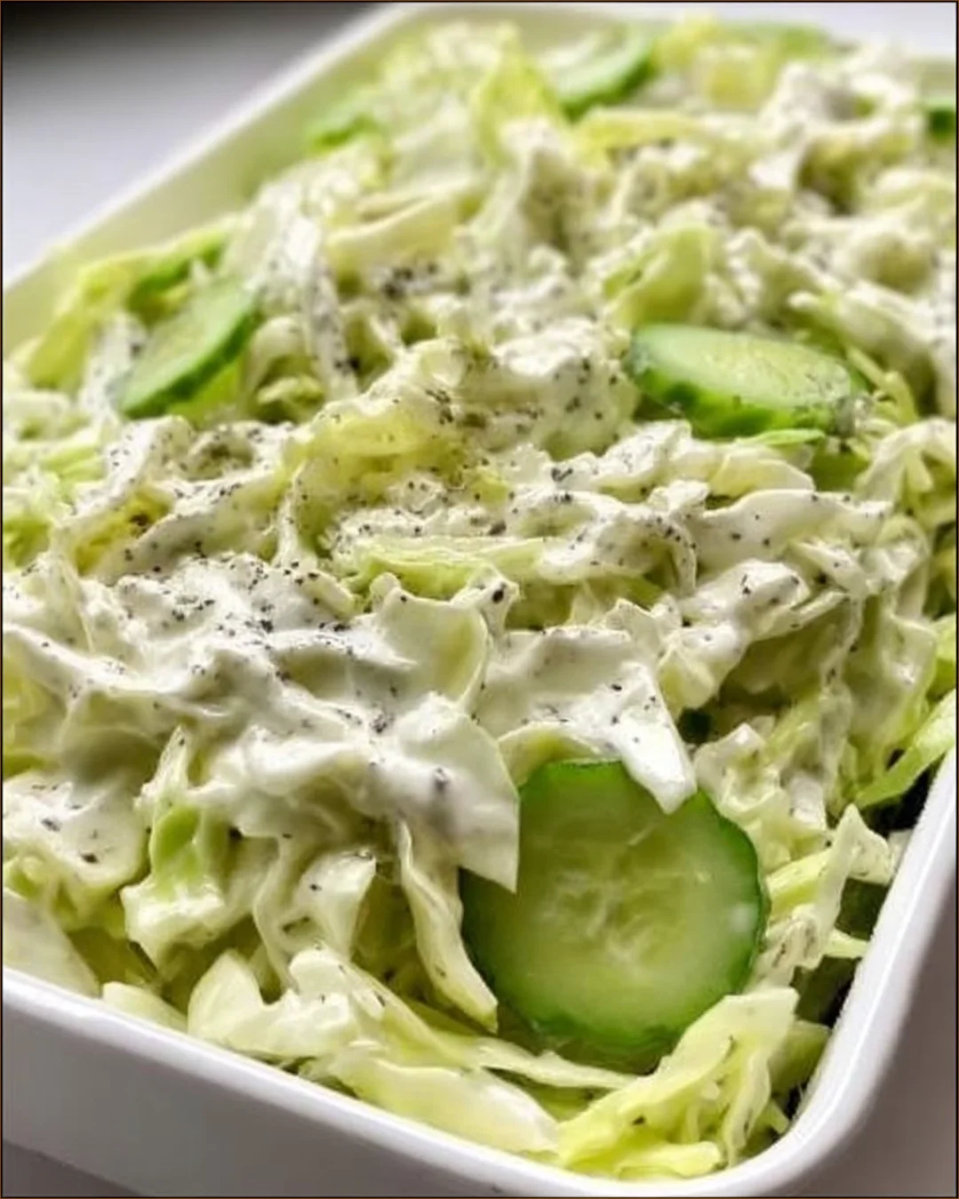 Creamy peppery coleslaw with cucumbers and celery in a bowl