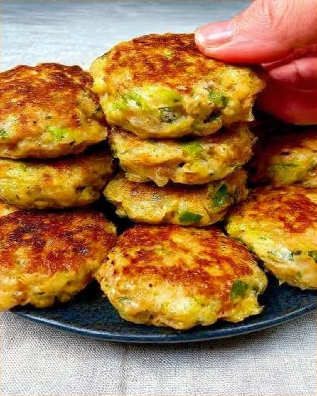 Crispy zucchini meatballs served on a plate with fresh herbs.